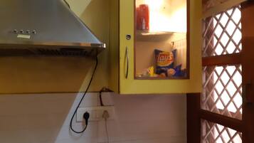 A kitchen with a yellow cabinet containing snacks, a stove, and a power outlet.