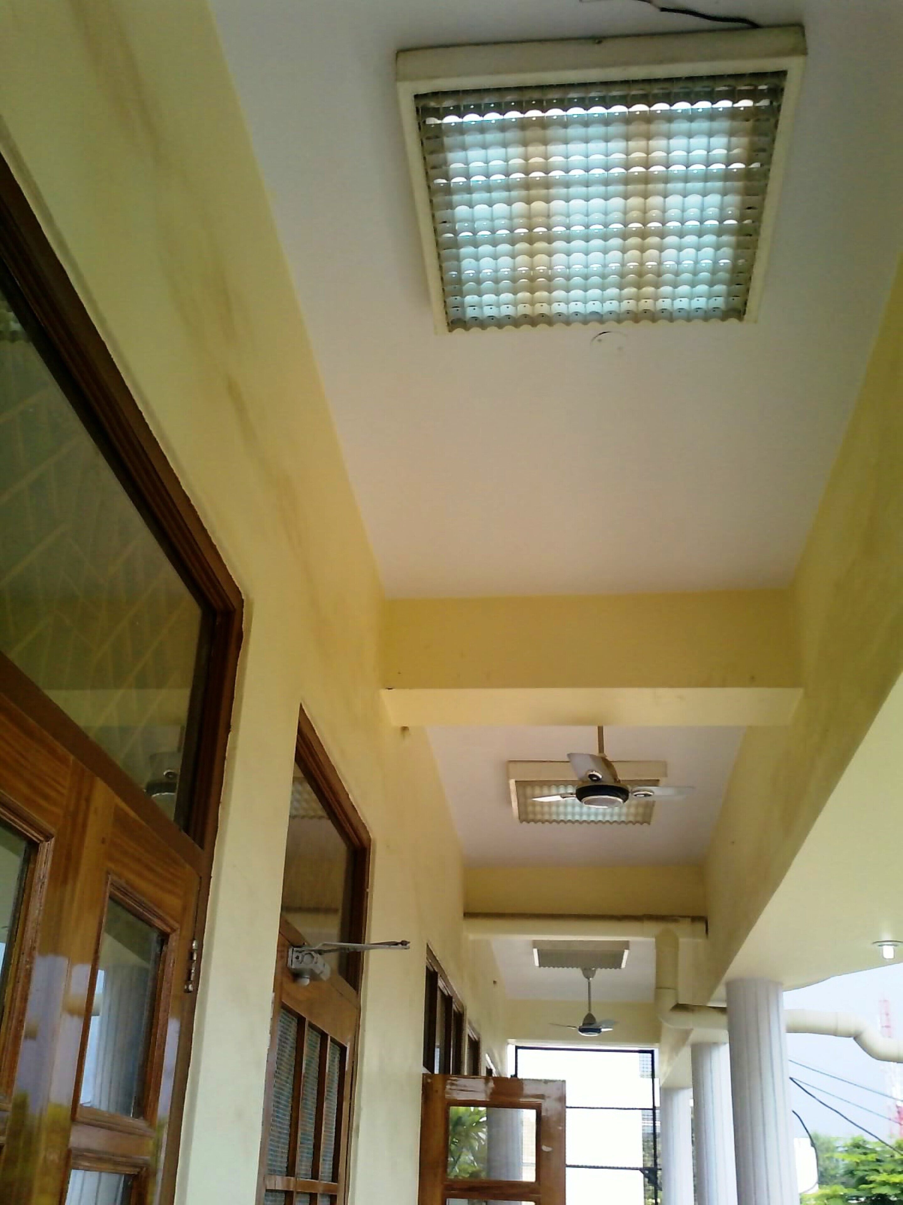 A corridor with a ceiling fan, a window with blinds, and a door leading to another room.