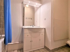Un baño con tocador blanco, espejo y bañera.