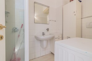 Un baño con cabina de ducha de vidrio, un lavabo, un espejo y un inodoro.