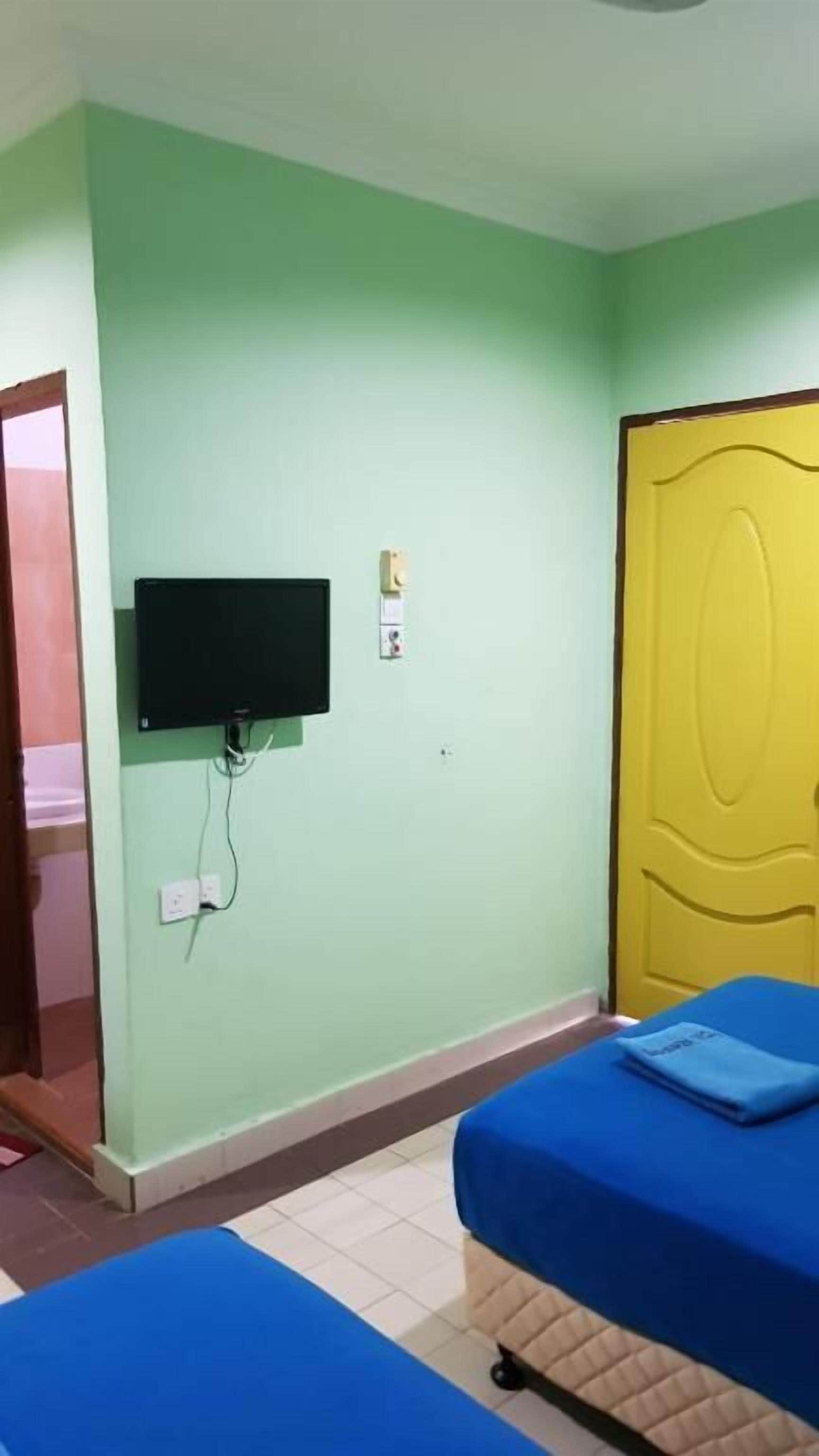 Een kamer met een bed, een aan de muur bevestigde televisie en een deur.