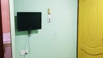 Een kamer met een bed, een aan de muur bevestigde televisie en een deur.
