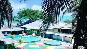 Un área de piscina con varias piscinas y un colorido suelo de azulejos.