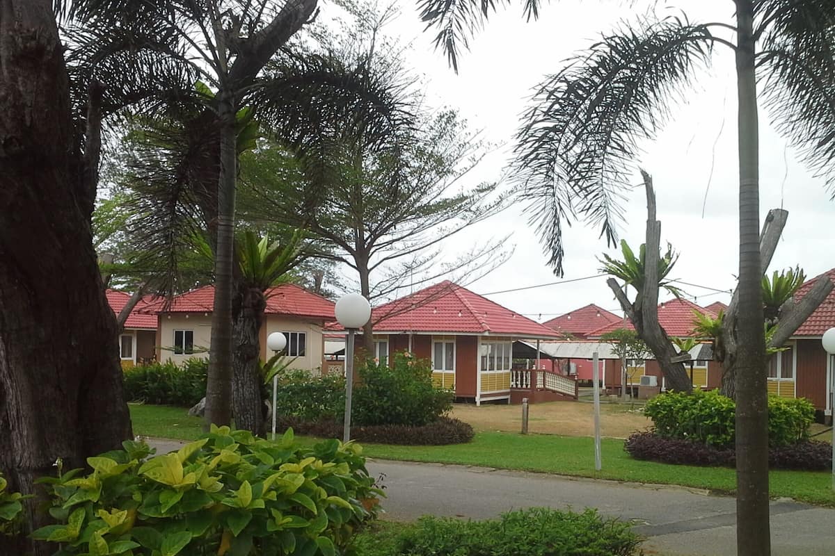 A row of red-roofed buildings with a paved walkway and greenery in the foreground.