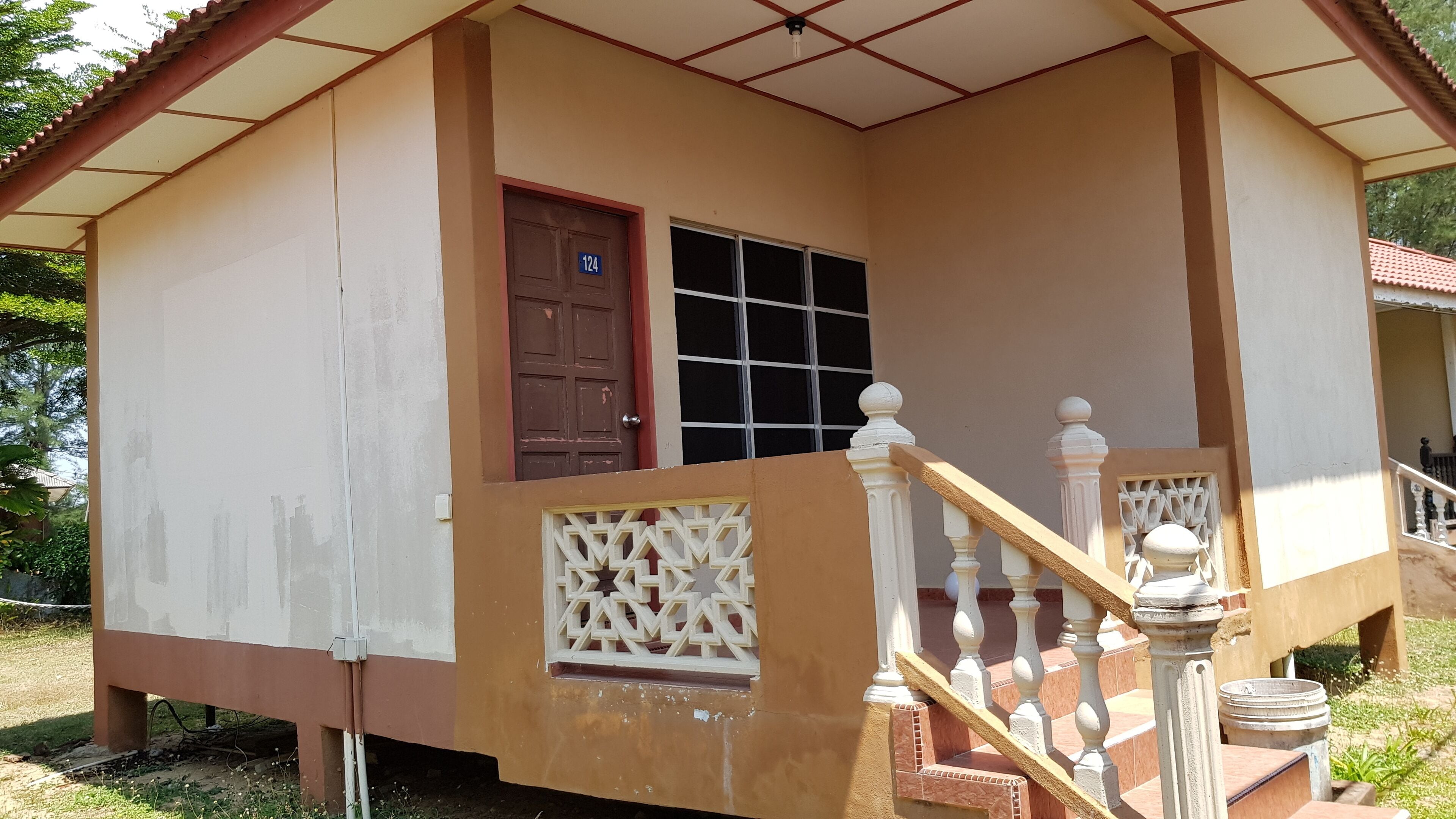 A single-story house with a brown door, a window, and a staircase with white balusters.