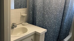 Ein Badezimmer mit einem weißen Waschbecken, einem Spiegel, einem Handtuchhalter und einer blauen Duschvorhang.