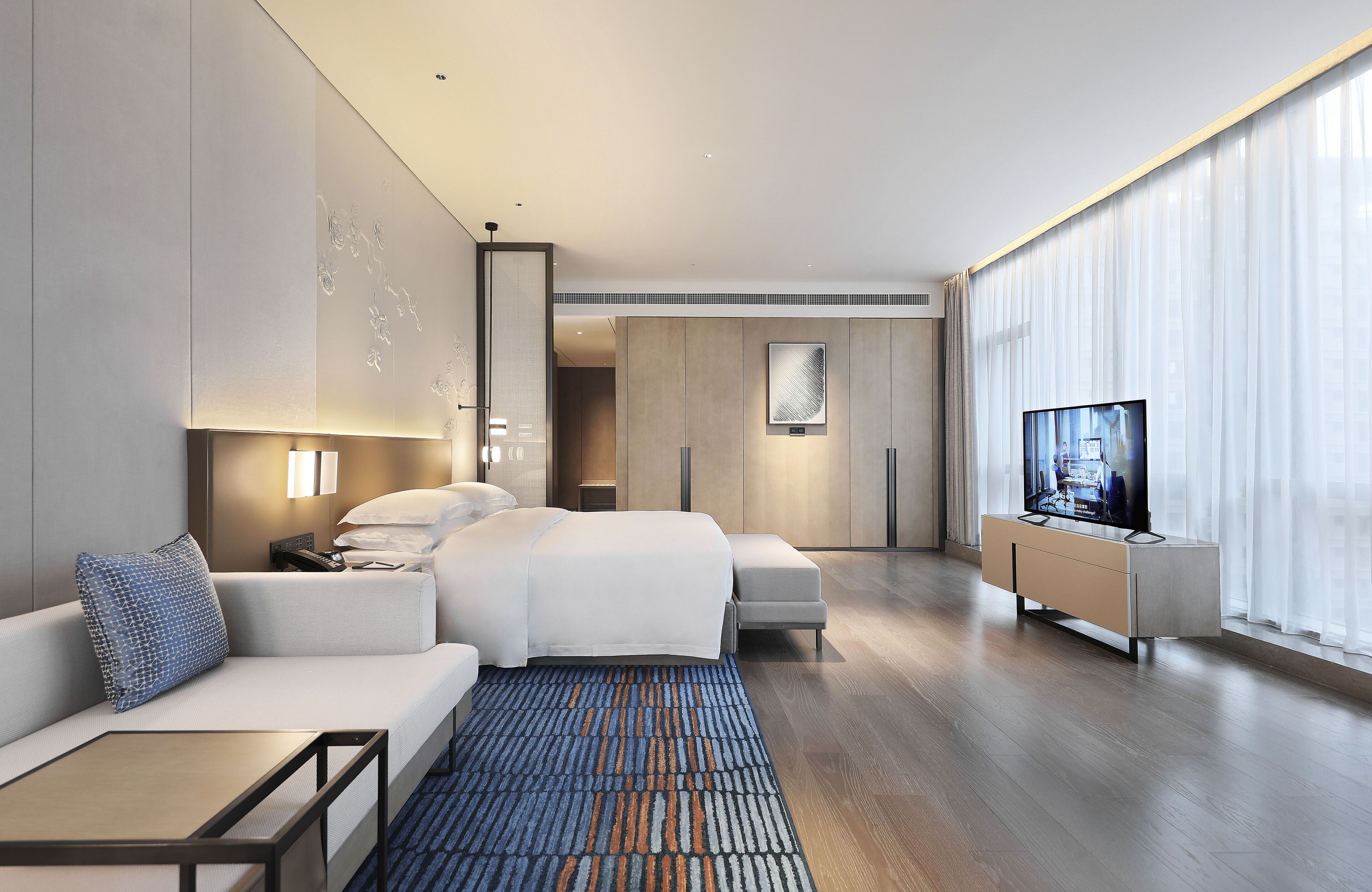 Une chambre d’hôtel moderne équipée d’un grand lit, d’un canapé, d’une télévision et d’un bureau.