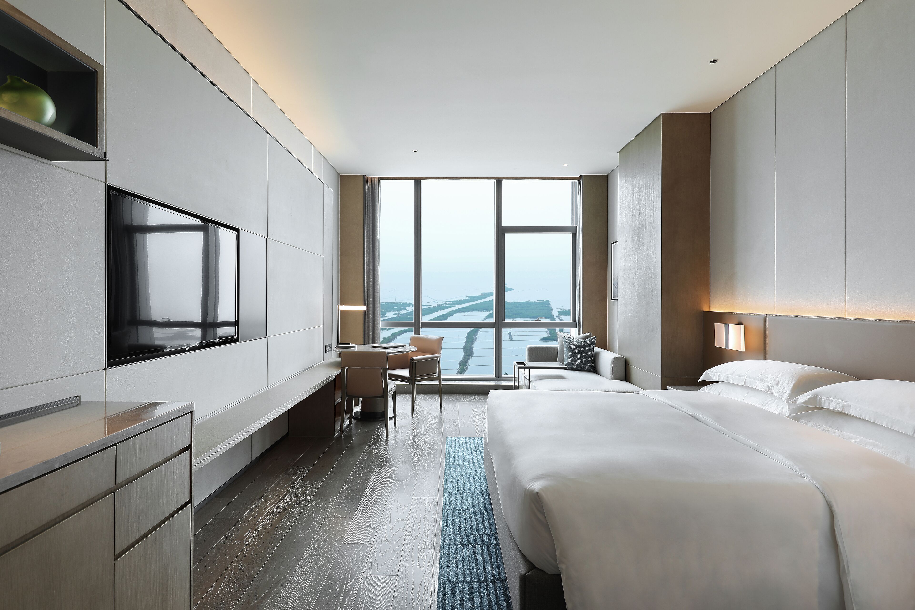 Una habitación de hotel moderna con una cama grande, un escritorio y un televisor.