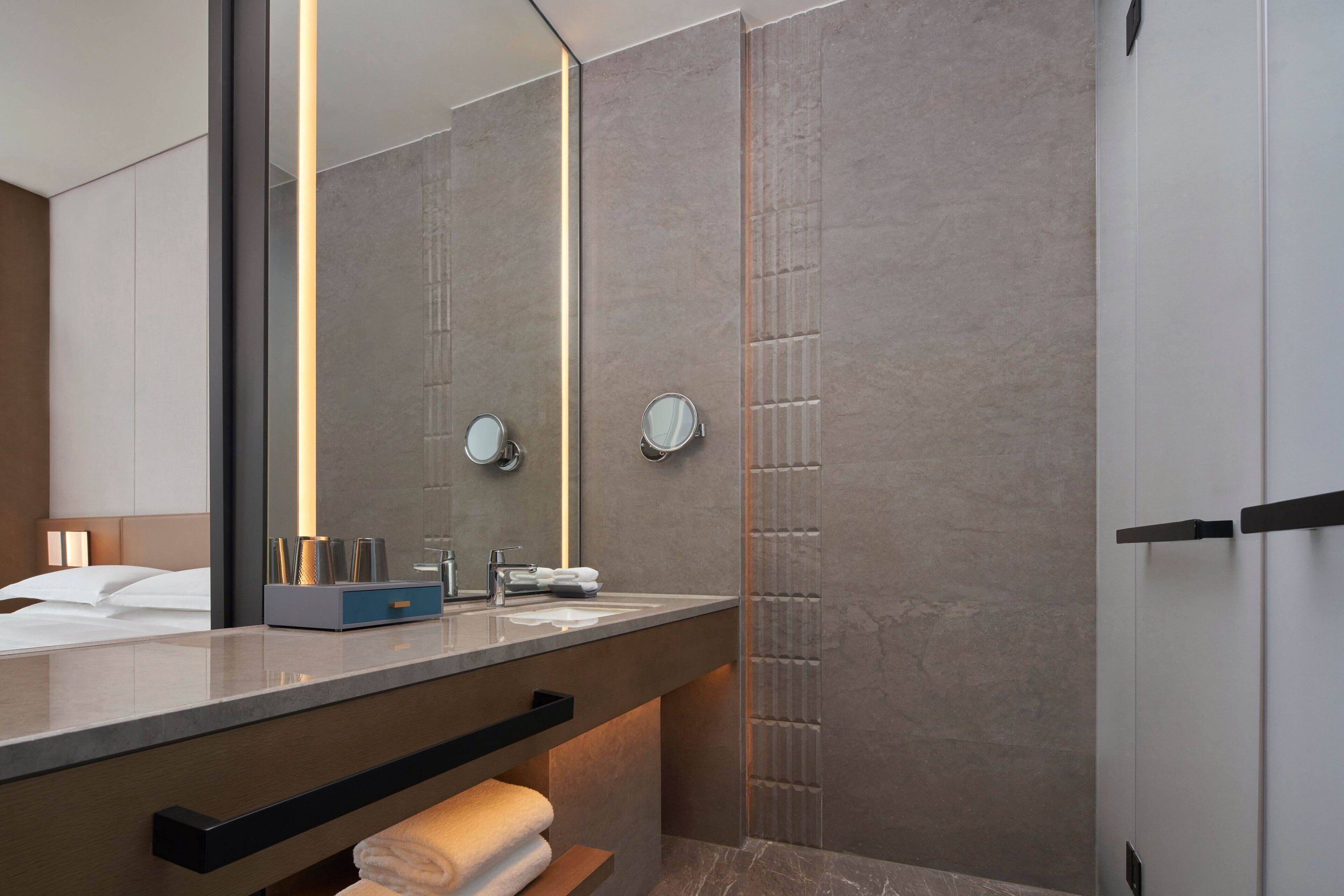 Un baño moderno con un espejo grande, un lavamanos y un perchero para toallas.