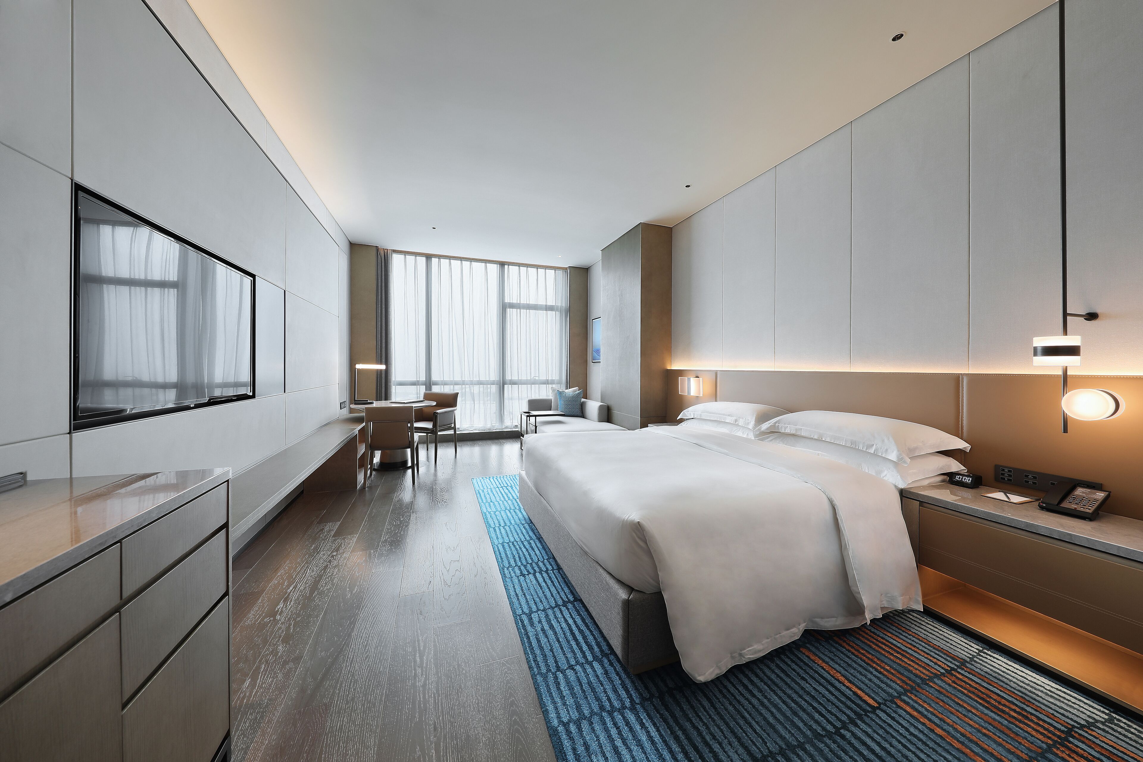 Una habitación de hotel moderna con una cama grande, mesita de noche y una zona de escritorio.