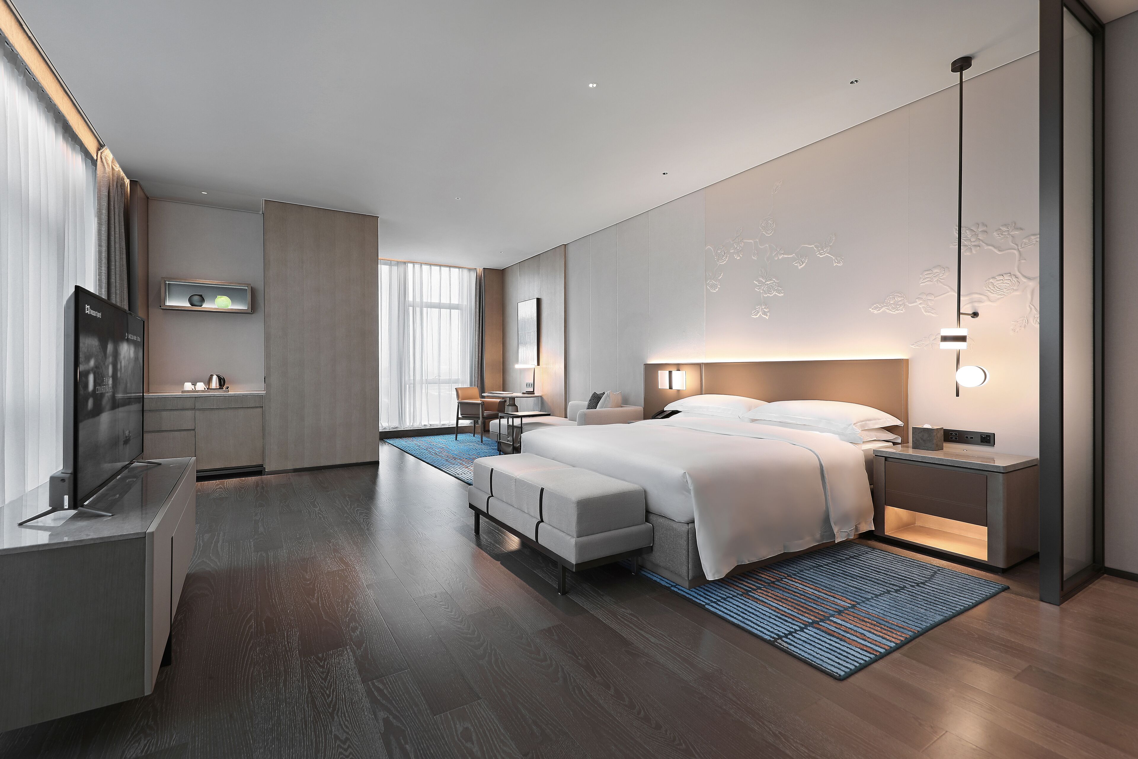 Una habitación de hotel moderna con una cama grande, mesitas de noche, televisión, escritorio y baño.