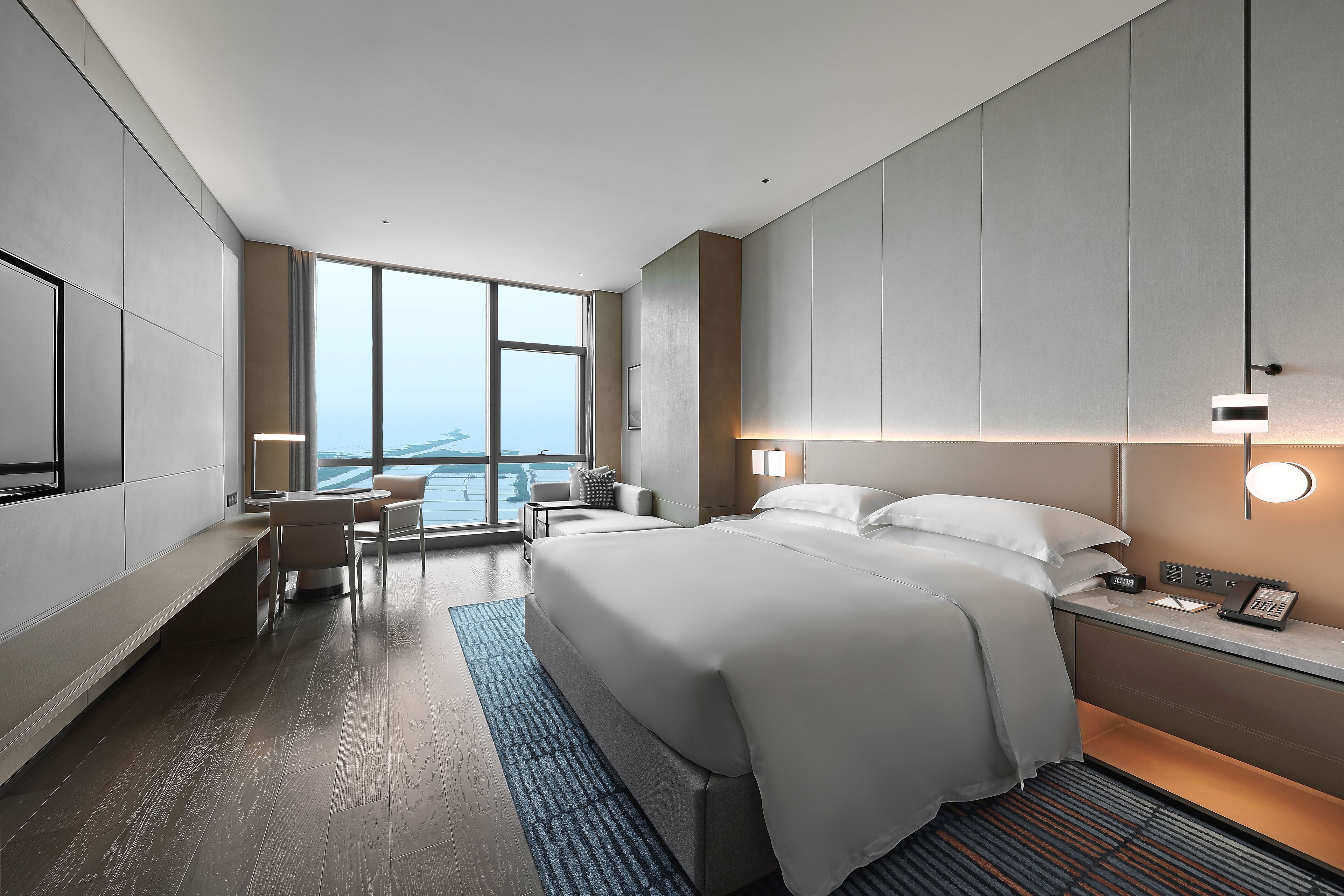 Una habitación de hotel moderna con una cama grande, un escritorio y vistas a la ciudad.