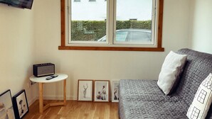 Ett sovrum med en säng, ett litet bord, en tv och inramade bilder på väggen.