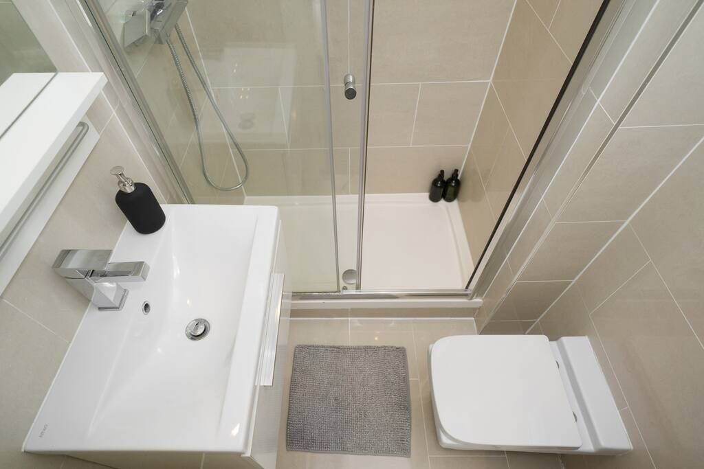 A modern bathroom with a glass-enclosed shower, a white sink, and a toilet.