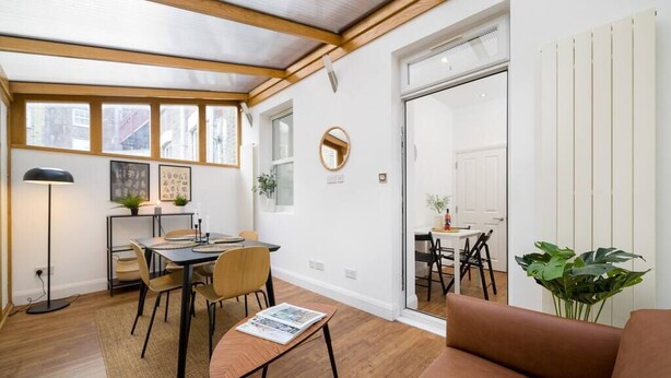 A modern interior with a dining area, a sofa, and a plant.
