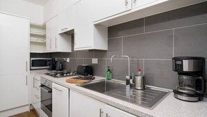 A modern kitchen with white cabinets, a stainless steel sink, a coffee maker, and a microwave.