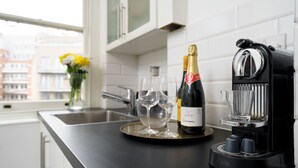 Une cuisine moderne avec une machine à café, une bouteille de vin et des verres disposés sur un plateau.