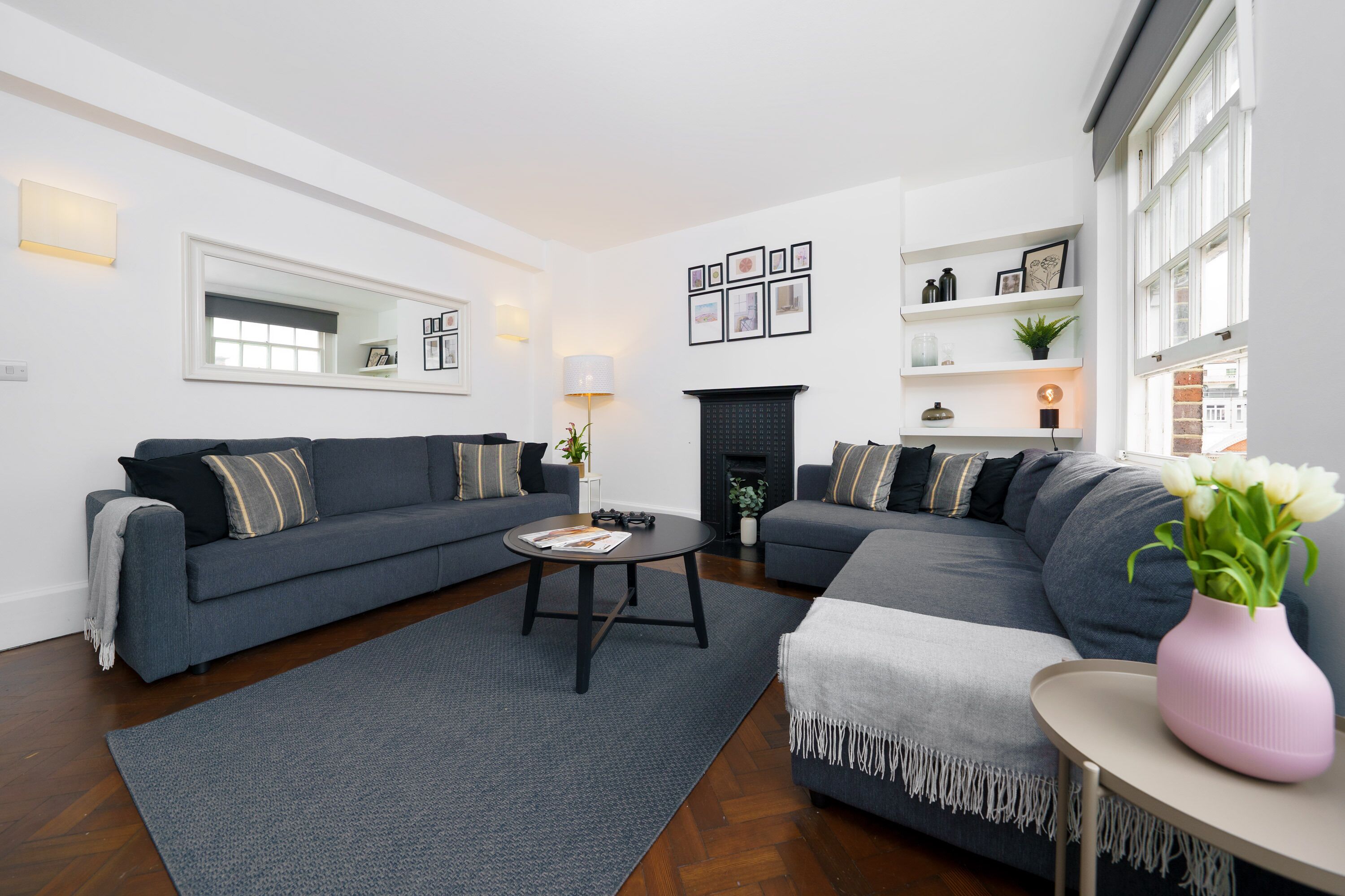 A modern living room with two grey sofas, a coffee table, and a fireplace.