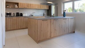Uma cozinha moderna com armários de madeira, uma ilha central e eletrodomésticos embutidos.