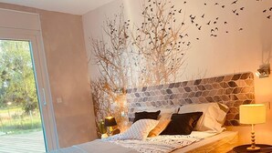 Quarto com cama, uma cadeira, luminária e parede com padrão de pedra.