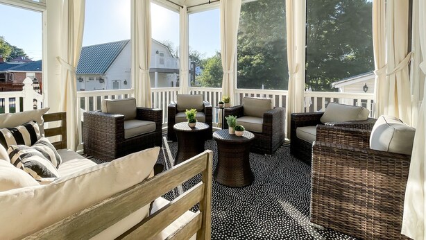 A sunlit room with wicker furniture, a ceiling fan, and large windows offering a view of the neighborhood. - Mill Haus - Heated Swimming Pool, Hot Tub, Dog Friendly, Downtown (Washington)