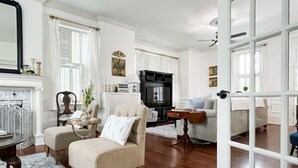 A living room with a fireplace, a television, and a dining area with a table and chairs. - Mill Haus - Heated Swimming Pool, Hot Tub, Dog Friendly, Downtown (Washington)