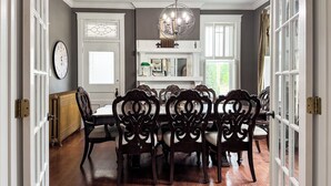 A dining room with a round table, ornate chairs, a chandelier, and a view of the outdoors through a window. - Mill Haus - Heated Swimming Pool, Hot Tub, Dog Friendly, Downtown (Washington)