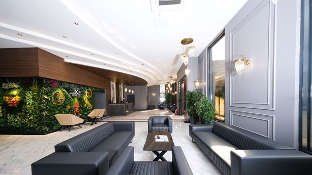 Un moderno vestíbulo de hotel con una pared verde, zona de estar y mostrador de recepción.