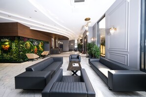 Un moderno vestíbulo de hotel con una pared verde, zona de estar y mostrador de recepción.