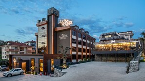 Un hotel con un letrero llamativo, un área exterior cubierta y un estacionamiento.
