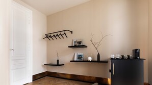 Une cuisine moderne avec un réfrigérateur noir, un plancher en bois et un décor minimaliste comprenant un porte-ustensiles suspendu et des étagères avec des livres et des objets décoratifs.
