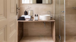Een moderne badkamer met een grote spiegel, een wastafel en een douche met glazen wanden.