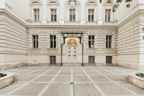 Ein Innenhof mit einem zentralen Eingang, gesäumt von symmetrischen Fenstern und einem dekorativen Bogen.