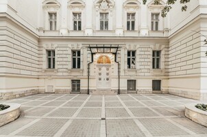 Pátio com entrada central, ladeado por janelas simétricas e um arco decorativo.
