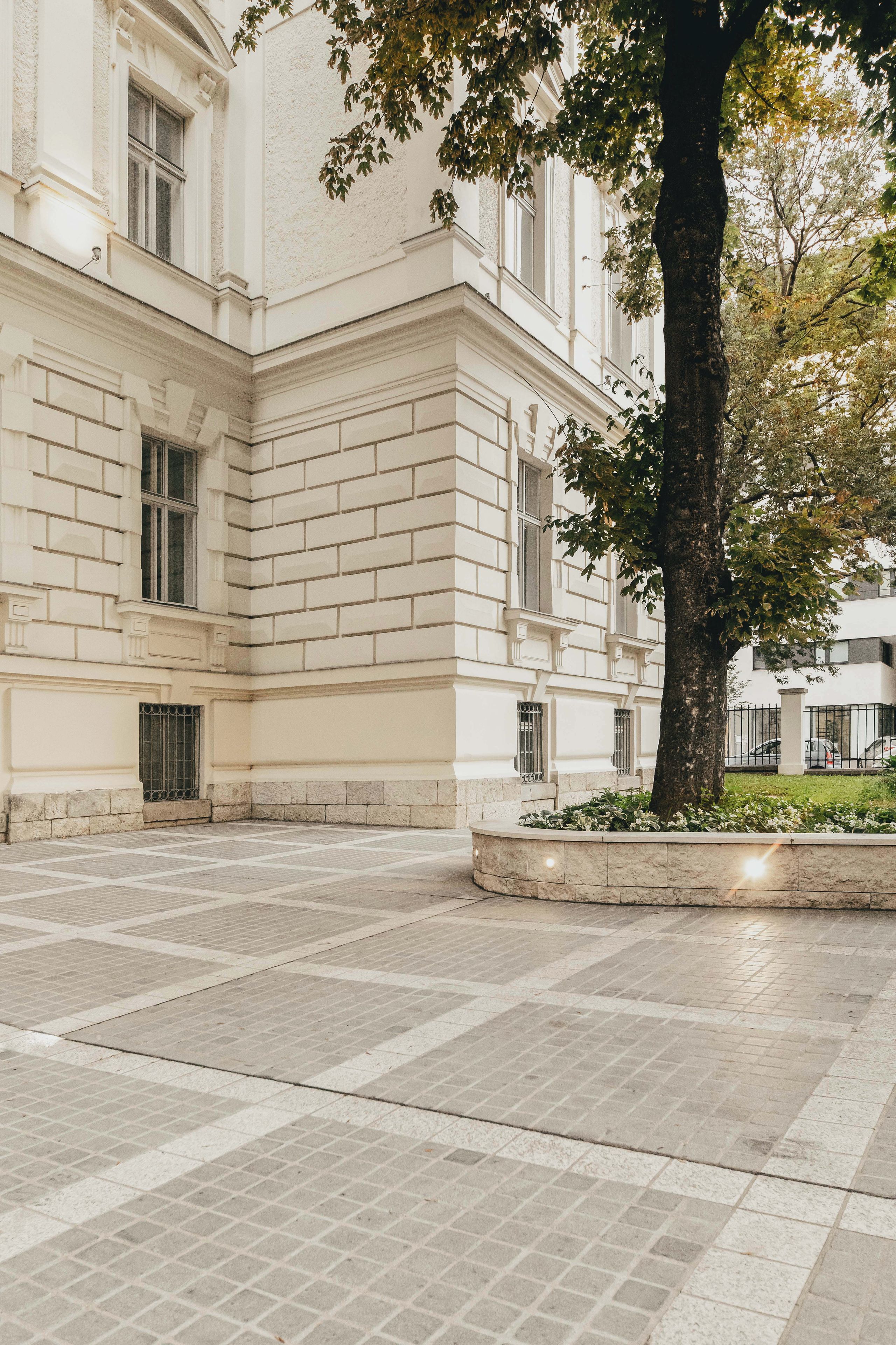 A building with a symmetrical facade, large windows, and a paved courtyard.