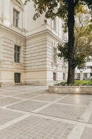 A building with a symmetrical facade, large windows, and a paved courtyard.