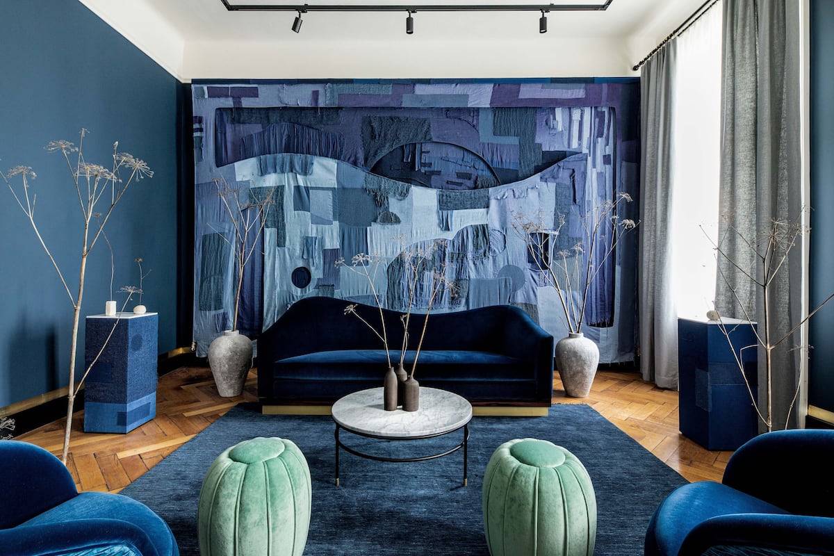 Un salon moderne avec un canapé bleu, une table basse ronde et des poufs verts.