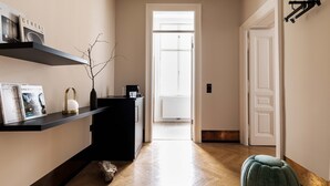 Un couloir avec une console noire, un pouf vert et une porte blanche au fond.