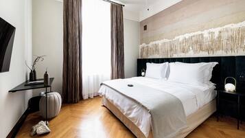 Ein modernes Hotelzimmer mit einem großen Bett, einem Nachttisch, einem Sessel, einem kleinen Tisch und einer Wandleuchte.