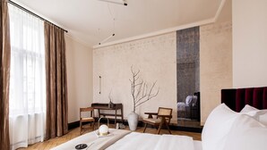 Une chambre d’hôtel avec un lit, un bureau, une chaise, un vase et un tableau au mur.