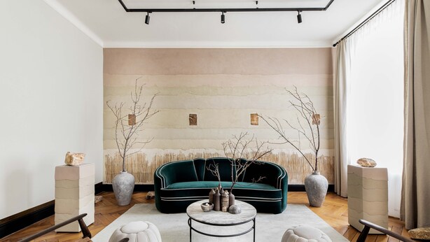 Un salon moderne avec un canapé vert, une table basse ronde et deux petites tables d’appoint.