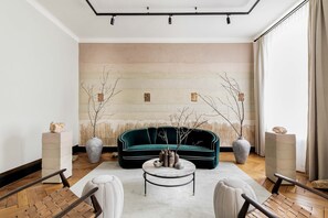 Een moderne woonkamer met een groene bank, een ronde salontafel en twee bijzettafels.