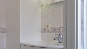 A bathroom with a white sink, a mirror, and a tiled backsplash. - Quietly situated maisonette apartment in Prerow, 4 pers., parking lot, WLAN, laundry incl. (Ostseebad Prerow)