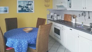 A dining area with a round table covered by a blue tablecloth, surrounded by wicker chairs. - Quietly situated maisonette apartment in Prerow, 4 pers., parking lot, WLAN, laundry incl. (Ostseebad Prerow)