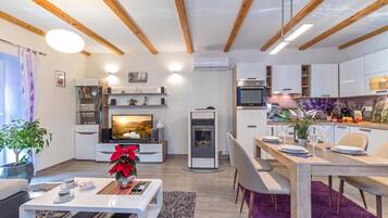 Una sala de estar moderna con televisor, chimenea y comedor con mesa lista para dos.