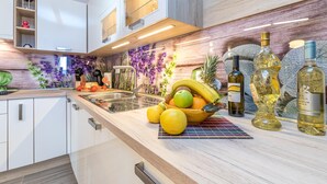 A modern kitchen with white cabinetry, a fruit bowl, and wine bottles. - Holiday Home Kastav (Kastav)