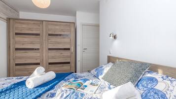 Un dormitorio con cama, armario de madera, una puerta y una lámpara fijada a la pared.