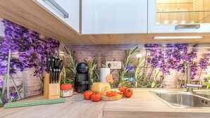 A modern kitchen with a wooden countertop, a built-in sink, and a decorative wall with purple flowers. - Holiday Home Kastav (Kastav)