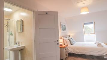 Un dormitorio con cama, mesita de noche, lámpara y ventana.