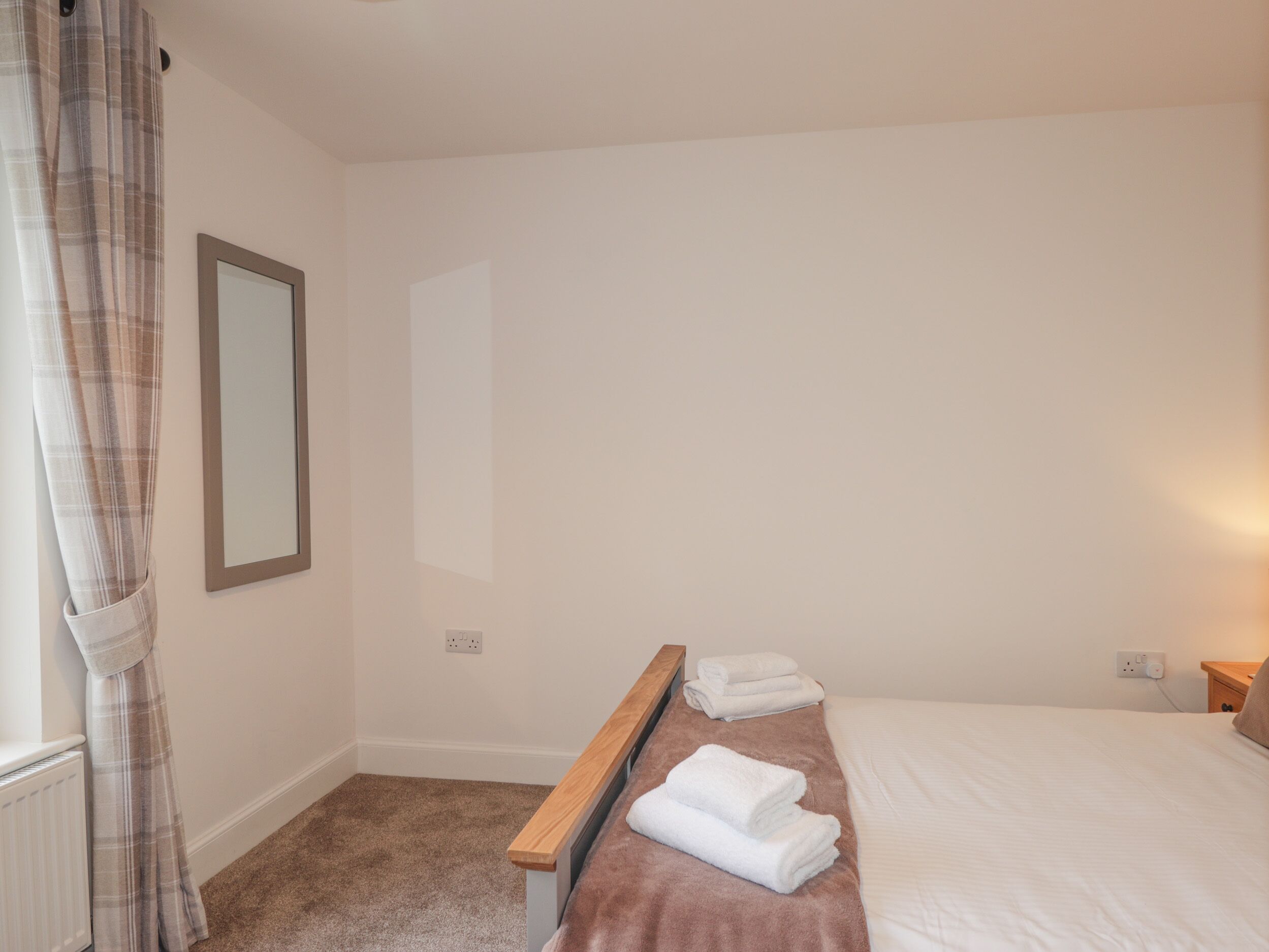 Un dormitorio con una cama, un banco de madera y un espejo en la pared.